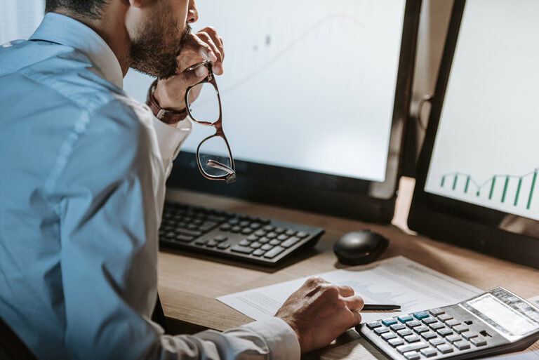 cropped view of bi-racial trader looking at computer and holding